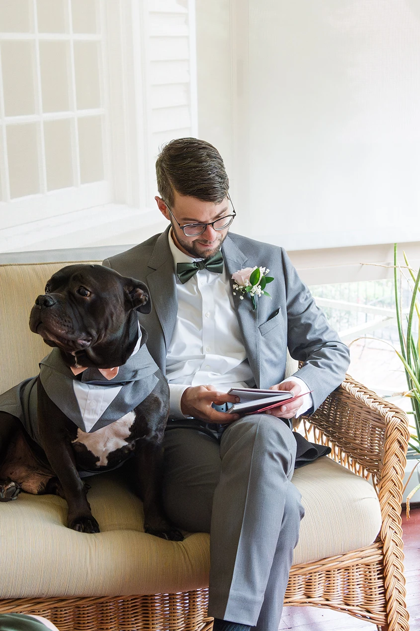 Groom with his best canine companion on a couch looking at a book