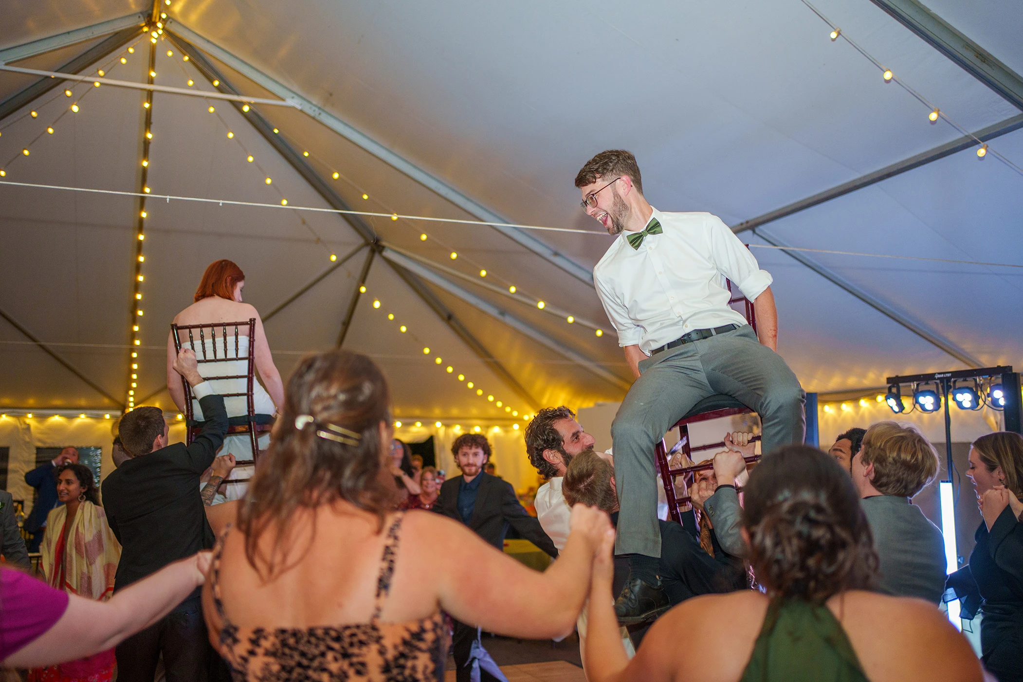 Bride and Groom on chairs being held up during the hora