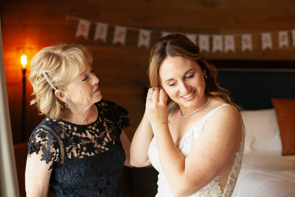 A quiet, meaningful moment as a mother helps her daughter put on her earrings before the wedding ceremony at the Ghost Light Inn in New Hope, Pennsylvania.