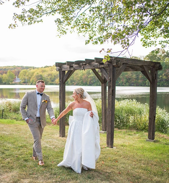 Bride and groom walking hand in hand at Trout Lake in Stroudsburg, PA
