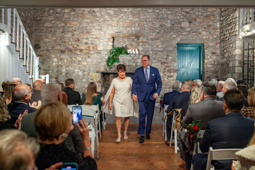 A couple walks down the aisle after their ceremony inside the Old Barn at Holly Hedge Estate in New Hope, Pennsylvania, surrounded by family and friends.